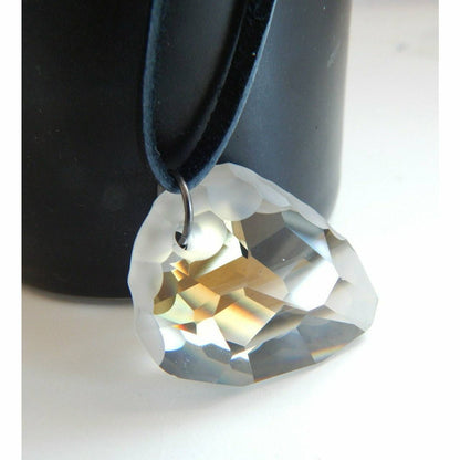 Colgante de cristal de roca sobre collar de cuero negro.